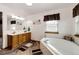 Bright bathroom showcasing a double vanity, a soaking tub, and sleek wood-look floors at 1853 Burton St, Strasburg, CO 80136