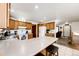 Bright kitchen featuring a breakfast bar, white appliances, wood cabinets, and access to a cozy living room at 1853 Burton St, Strasburg, CO 80136