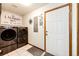 Convenient laundry room with modern washer and dryer, white door, and 'Laundry Room' wall art at 1853 Burton St, Strasburg, CO 80136