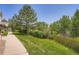 Spacious backyard featuring lush green grass and mature trees, complemented by a walking path at 22560 E Ontario Dr # 204, Aurora, CO 80016
