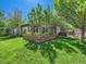 Large backyard featuring a lush green lawn, patio, and a hot tub at 6366 Umber Cir, Arvada, CO 80403