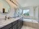 Light-filled primary bathroom with a double vanity, framed mirrors, and a luxurious soaking tub at 6366 Umber Cir, Arvada, CO 80403