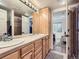 Bathroom features a double sink vanity with wood cabinets and view to bedroom at 6366 Umber Cir, Arvada, CO 80403