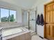 Light-filled bathroom featuring a soaking tub, glass enclosed shower and a large bright window at 6366 Umber Cir, Arvada, CO 80403