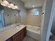 Bathroom featuring tub/shower combo with tile surround, vanity with sink, and large mirror with decorative lighting at 13013 Grant Cir # C, Thornton, CO 80241