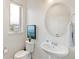 Bright bathroom with a pedestal sink, round mirror, and modern fixtures at 5668 Galena St, Denver, CO 80238