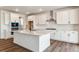 Bright kitchen features white cabinets, an island, stainless steel appliances, and hardwood floors at 25284 E Warren Pl, Aurora, CO 80018