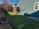 Expansive backyard with artificial turf and modern privacy screen leading to covered patio and lush garden at 9011 Sandpiper Dr, Longmont, CO 80504