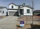 Charming two-story home featuring white siding, a gray garage door, and a well-manicured front yard at 1465 Bloom St, Brighton, CO 80601