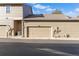 A beige one-car garage is attached to a tan home on a street of similar townhomes in a residential neighborhood at 7944 E Lowry Blvd, Denver, CO 80230