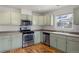 Modern kitchen with light green cabinets, stainless steel appliances and wood flooring at 7944 E Lowry Blvd, Denver, CO 80230