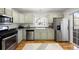 Well-maintained kitchen featuring stainless steel appliances, shaker cabinets, and wood-look flooring at 7944 E Lowry Blvd, Denver, CO 80230