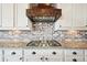 Close-up of a kitchen range hood with custom millwork and stainless steel appliances at 20223 Terrace View Dr, Parker, CO 80134