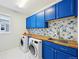 Charming laundry room features blue cabinets, floral backsplash, and modern appliances at 20223 Terrace View Dr, Parker, CO 80134