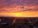 Wide view of a vivid sunset painting the sky with yellow and orange hues above residential rooftops at 20223 Terrace View Dr, Parker, CO 80134