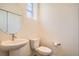 Modern half-bathroom with a pedestal sink, toilet, and a round mirror on the wall at 12898 King St, Broomfield, CO 80020