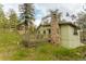Side view of the home with wood siding, a stone chimney, and a partially fenced in patio area at 4850 Forest Hill Rd, Evergreen, CO 80439
