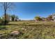 Expansive grassy backyard features a rustic wooden fence, trees, and a deck perfect for outdoor enjoyment at 18128 Sage Brush Way, Brighton, CO 80603