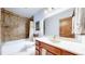 Bathroom featuring a shower with stone tile surround and a wood vanity cabinet at 12655 Greenland Acres Rd, Larkspur, CO 80118