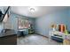 This bedroom has blue walls, gray carpet, and a desk by the window that looks out onto beautiful trees at 12655 Greenland Acres Rd, Larkspur, CO 80118