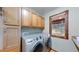 This laundry room has a large washer and dryer and an overhead cabinet at 12655 Greenland Acres Rd, Larkspur, CO 80118