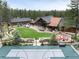 Aerial view of the home, basketball court, fire pit, manicured lawns, and surrounding forest at 44 N Big Meadow Trl, Franktown, CO 80116