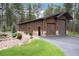 Exterior shot of a spacious wood garage with rock accents, offering ample parking and storage space at 44 N Big Meadow Trl, Franktown, CO 80116