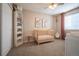 Bedroom with tan walls, plush carpet, a white bookcase, and a wooden crib centered in the room at 4927 Tarcoola Ln, Highlands Ranch, CO 80130