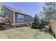 A well-kept lawn surrounds the house in this backyard, featuring a stone foundation and lush trees at 6821 W Yale Ave, Lakewood, CO 80227