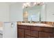 Bathroom with double sinks, wood cabinets, tile floors, and a large mirror complemented by natural light at 6821 W Yale Ave, Lakewood, CO 80227
