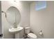 Clean half bathroom featuring a pedestal sink, a round mirror, and a toilet with a minimalist design at 8376 Lorenzo Ln # A, Highlands Ranch, CO 80129