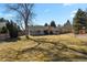 Spacious backyard with a large tree, lush lawn, and a charming single-Gathering house in the background at 9161 W Hialeah Pl, Littleton, CO 80123