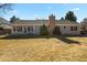 Expansive backyard featuring a brick chimney, mature trees, and ample space for outdoor activities at 9161 W Hialeah Pl, Littleton, CO 80123