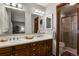 Bathroom featuring double sinks, wood cabinets, and a glass-enclosed shower at 9161 W Hialeah Pl, Littleton, CO 80123