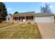 Charming brick home with a covered front porch, a well-manicured lawn, and an attached two-car garage at 9161 W Hialeah Pl, Littleton, CO 80123