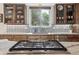 Lovely kitchen featuring a gas cooktop island, tile backsplash, modern appliances, and lots of natural light from the window at 5085 Red Rock Dr, Larkspur, CO 80118