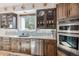 Charming kitchen with stainless steel appliances, light countertops, display cabinets and warm wood cabinetry giving it a cozy feel at 5085 Red Rock Dr, Larkspur, CO 80118
