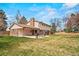 A wide backyard view of a home and patio with a grill, trees, and lush green lawn at 6196 S Rosewood Dr, Littleton, CO 80121