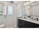 Bright bathroom with white subway tile, a glass-enclosed shower, and a double vanity with black cabinets at 2321 Alton St, Denver, CO 80238