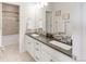 Well-lit bathroom with dual sinks with granite countertops, white cabinets, and tiled floors creating a clean and functional space at 3231 Riverwood Way, Castle Rock, CO 80109