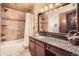 Bathroom featuring granite countertops, warm brown tones, a shower, and a large mirror at 3191 W 151St Ct, Broomfield, CO 80023