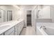 Bright bathroom featuring double sinks, quartz countertops, a glass shower, and a tub at 185 Ambrose St, Erie, CO 80516