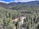 Breathtaking aerial view of a house nestled in a dense forest, surrounded by mountains at 205 Yankee Creek Trl, Evergreen, CO 80439