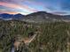 Breathtaking aerial view of a rustic home nestled in a forest with stunning mountain backdrops at 205 Yankee Creek Trl, Evergreen, CO 80439