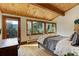 Bedroom with wood beam ceiling, three windows, and outside views at 205 Yankee Creek Trl, Evergreen, CO 80439