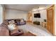 Carpeted living room with leather sofa, accent pillows, TV and decorative trunk at 205 Yankee Creek Trl, Evergreen, CO 80439