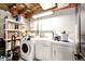 Basement laundry area with washer, dryer, and utility sink, featuring exposed ceiling beams at 8930 Apache Plume Dr, Parker, CO 80134