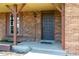 Close-up of a covered front porch with brick facade, wooden columns, and a dark-colored front door at 11098 Fairfax Way, Thornton, CO 80233