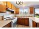 Functional kitchen with white appliances, wooden cabinets, and a window overlooking the backyard at 11098 Fairfax Way, Thornton, CO 80233