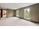 Living room featuring large windows, neutral carpet, and a glimpse into the kitchen area at 11098 Fairfax Way, Thornton, CO 80233